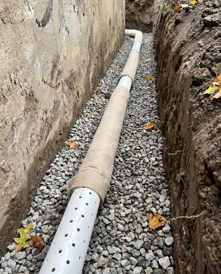 Perforated rigid drain laid on clear stone at the base of a foundation